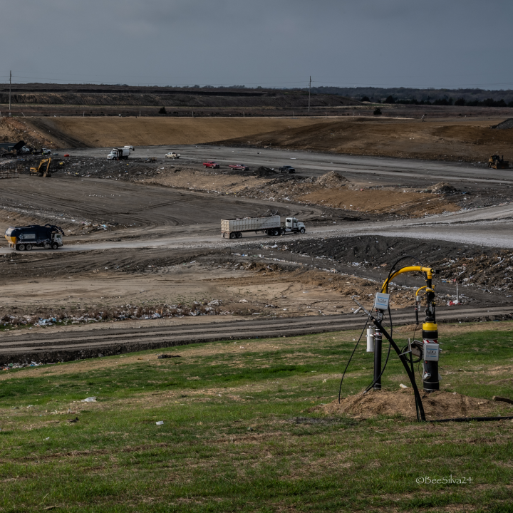 Wide view of methane extraction machine with trucks driving past